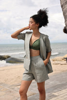 Woman in a gray blazer and shorts standing by the beach