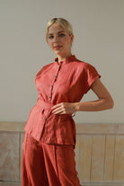 Woman wearing an outfit standing against a plain wall.