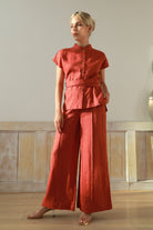 Woman wearing an outfit standing in a minimal indoor setting.