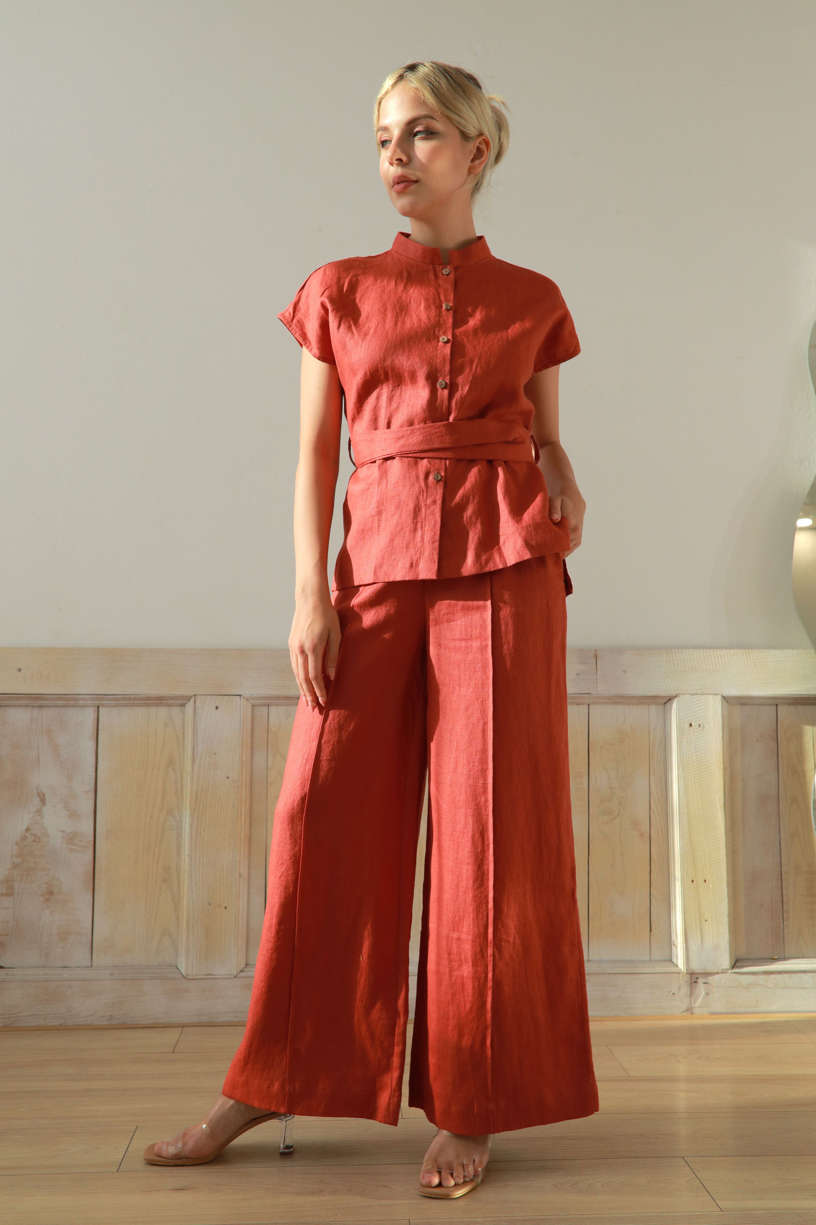 Woman wearing an outfit standing in a minimal indoor setting.