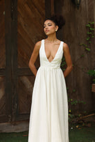 Woman in an ivory dress standing in front of a wooden door.
