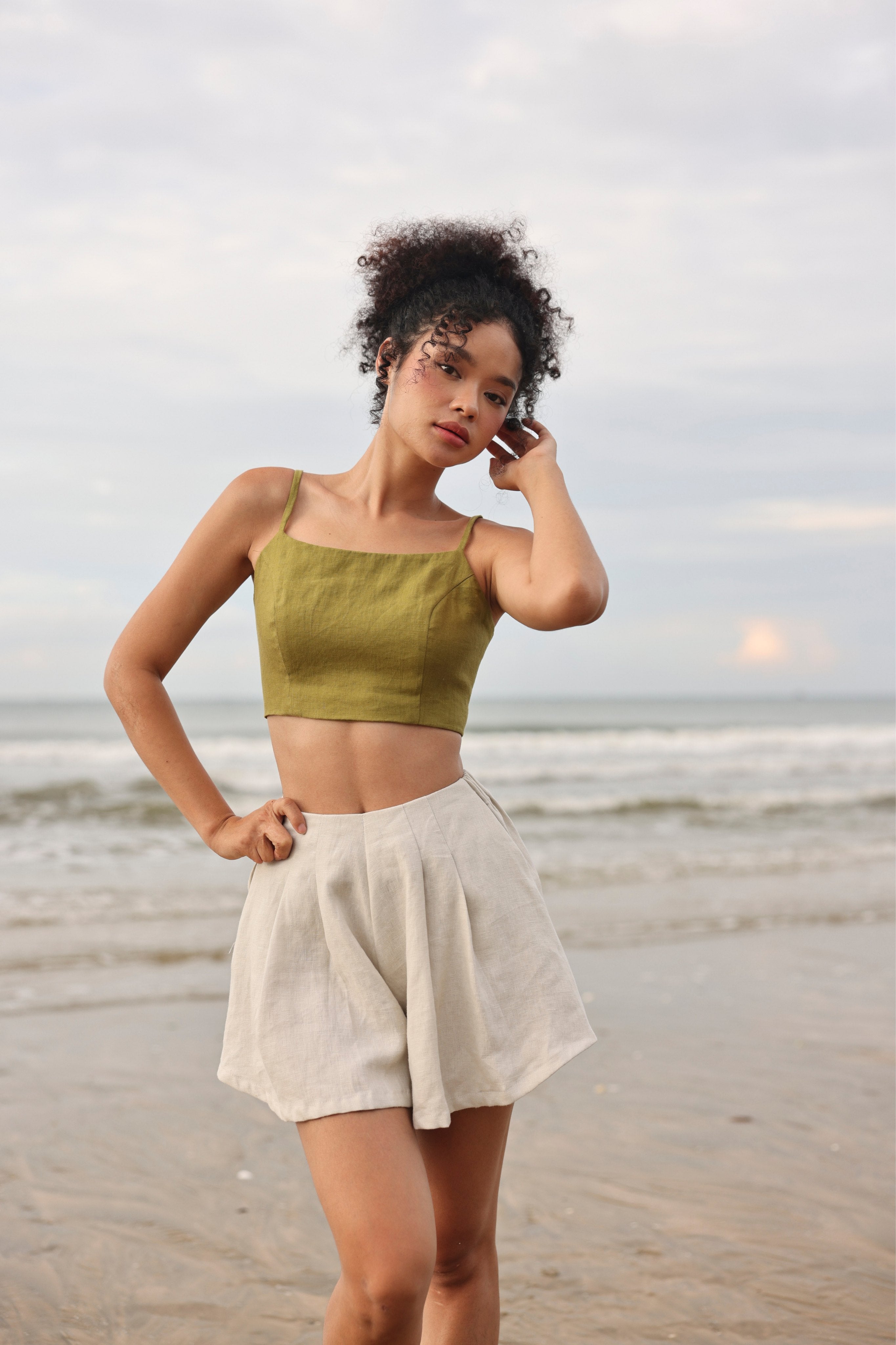 Woman in green top and beige shorts standing on a beach