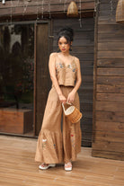 Woman in a beige outfit standing in front of a wooden wall.
