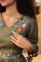 Woman wearing a green embroidered dress with a blurred background
