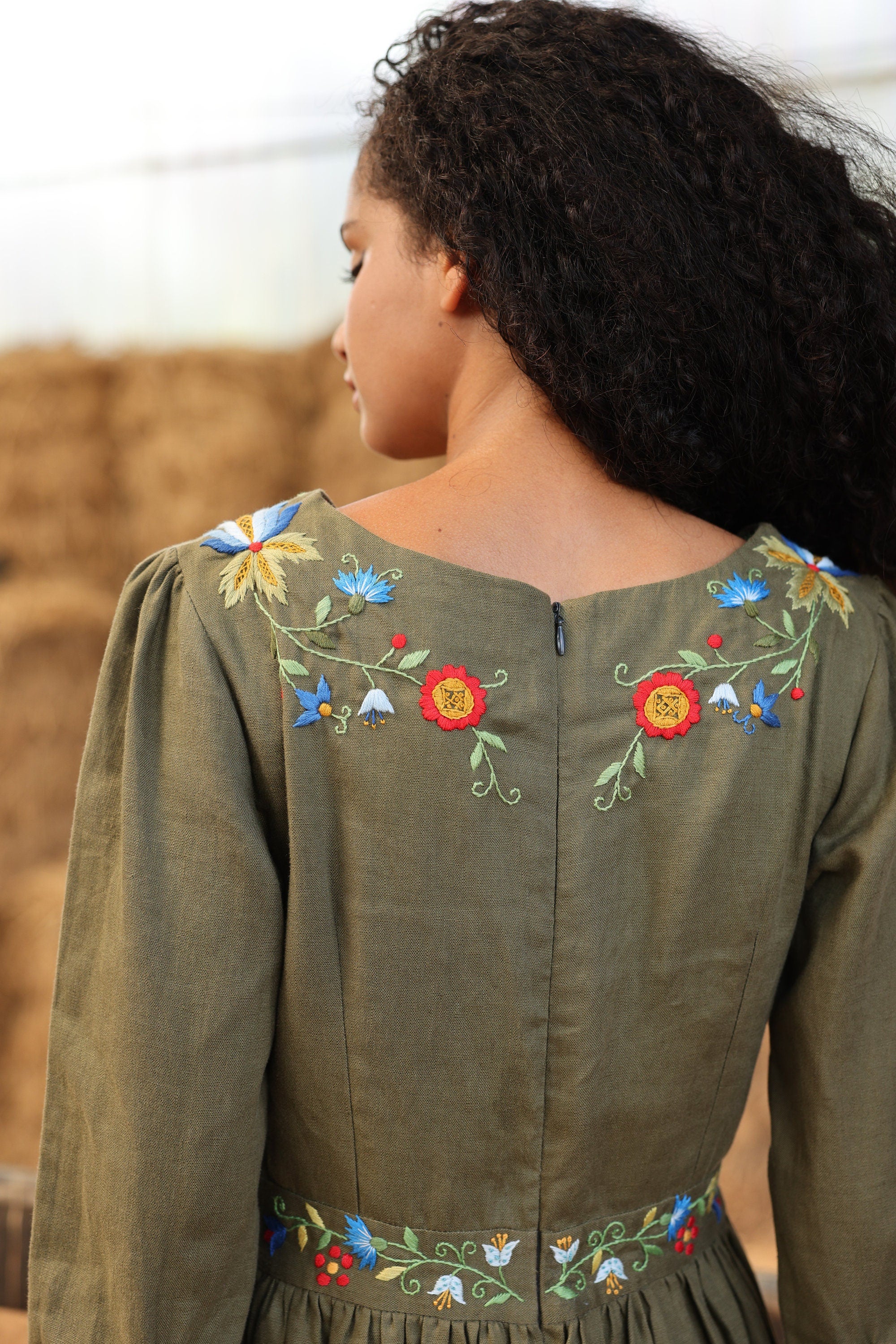 Person wearing a green dress with floral embroidery on the back