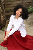 Woman wearing a white blouse and red skirt sitting outdoors.
