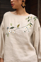 Beige blouse with floral embroidery worn by a person
