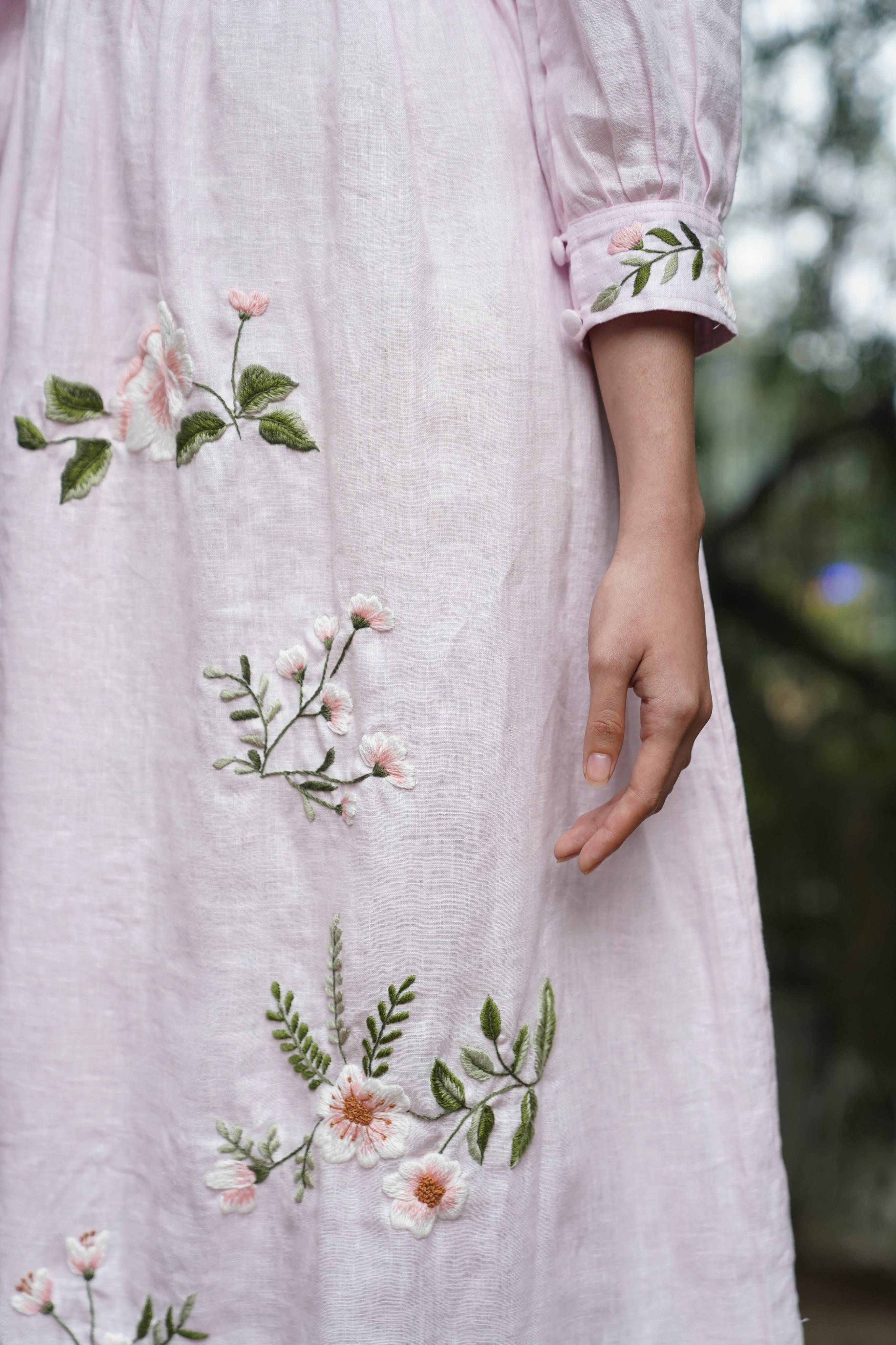 Light pink dress with floral embroidery on a blurred natural background