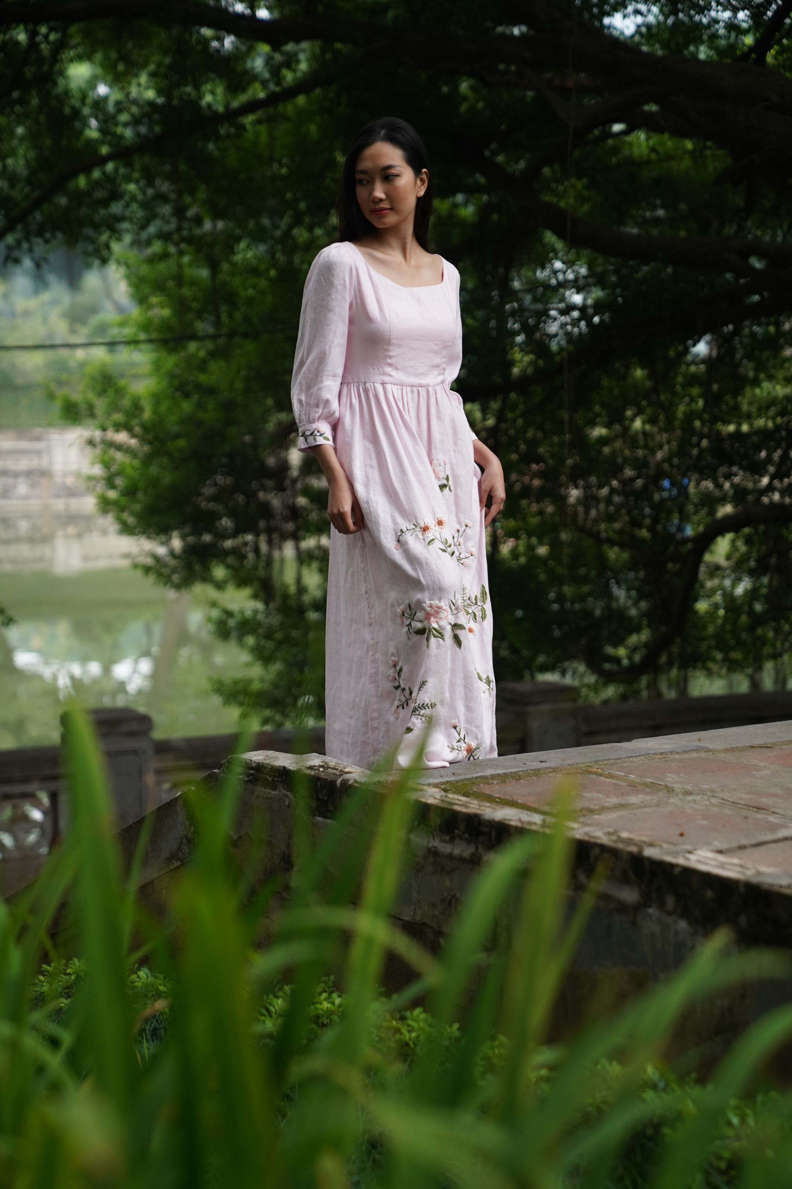 Woman in a floral dress standing outdoors with greenery around
