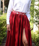 Person wearing a red skirt with floral waistband in an outdoor setting