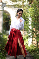 Woman in a white blouse and red skirt standing in a garden setting