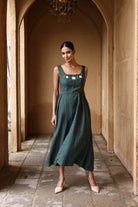 Woman in a green dress standing in an arched hallway