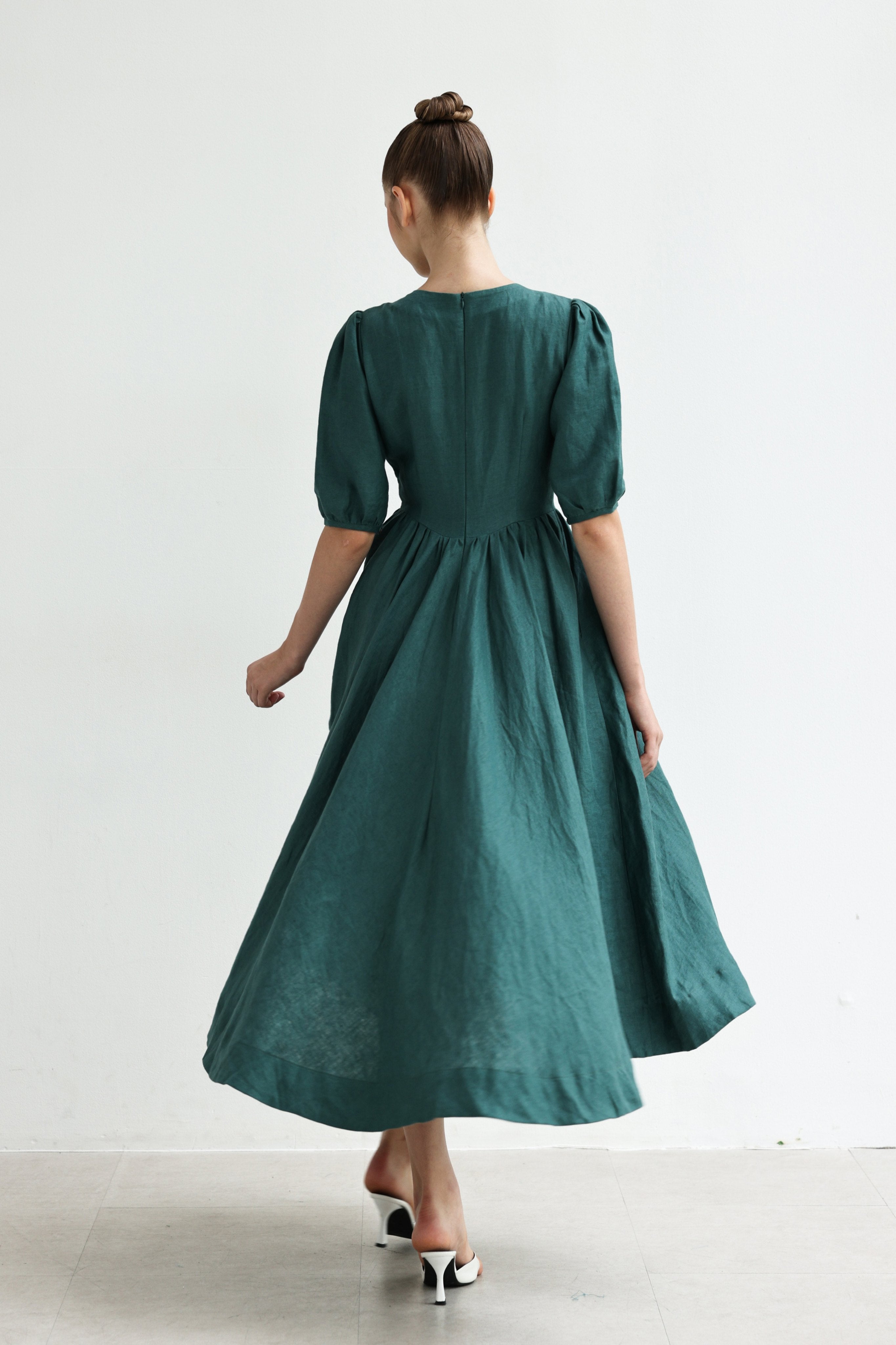 Woman wearing a green dress with puffed sleeves against a white background