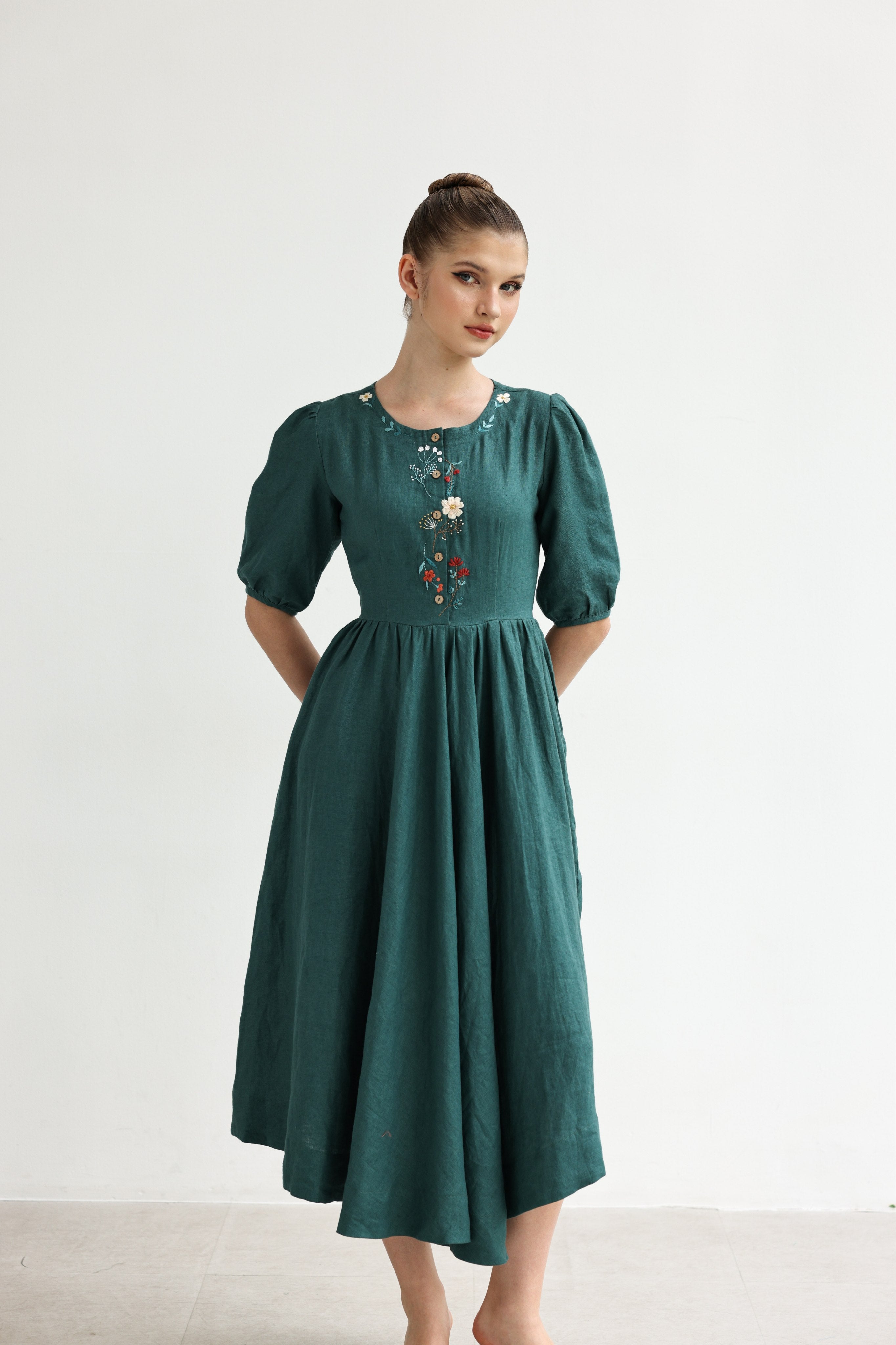 Woman wearing a green dress with floral embroidery on a white background