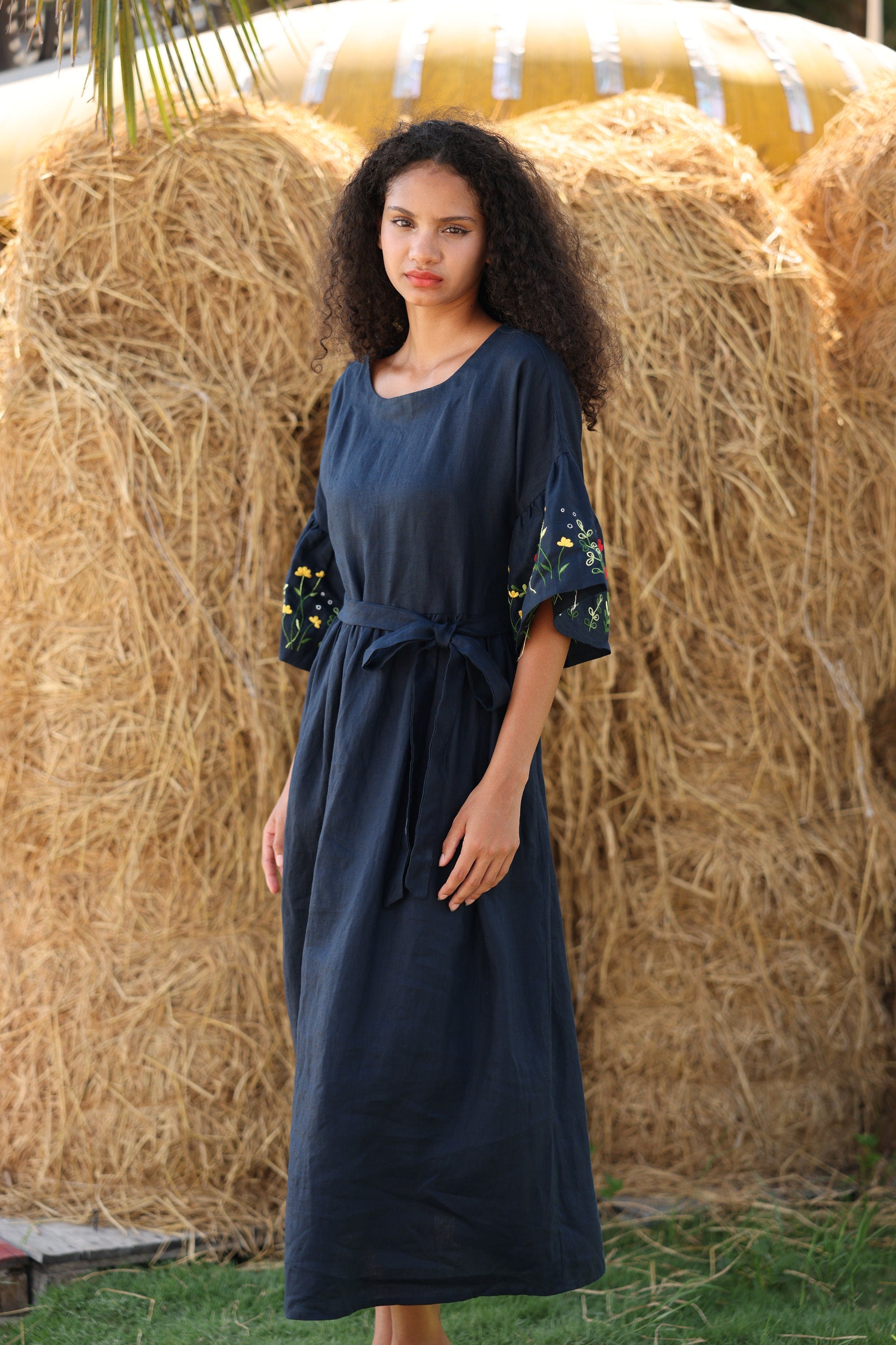 Woman in a navy blue dress standing in front of hay bales