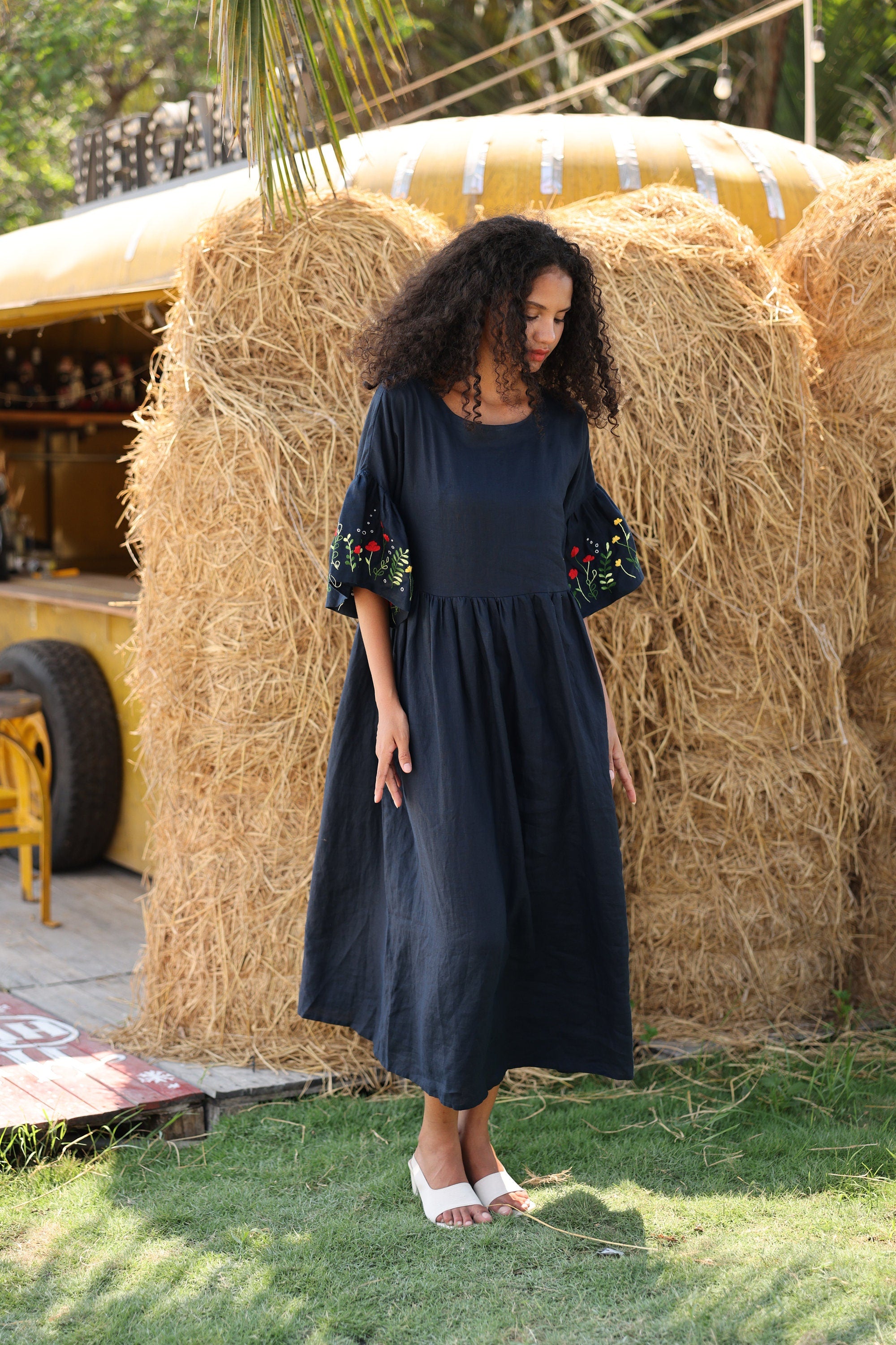 Woman in a navy dress standing in front of hay bales