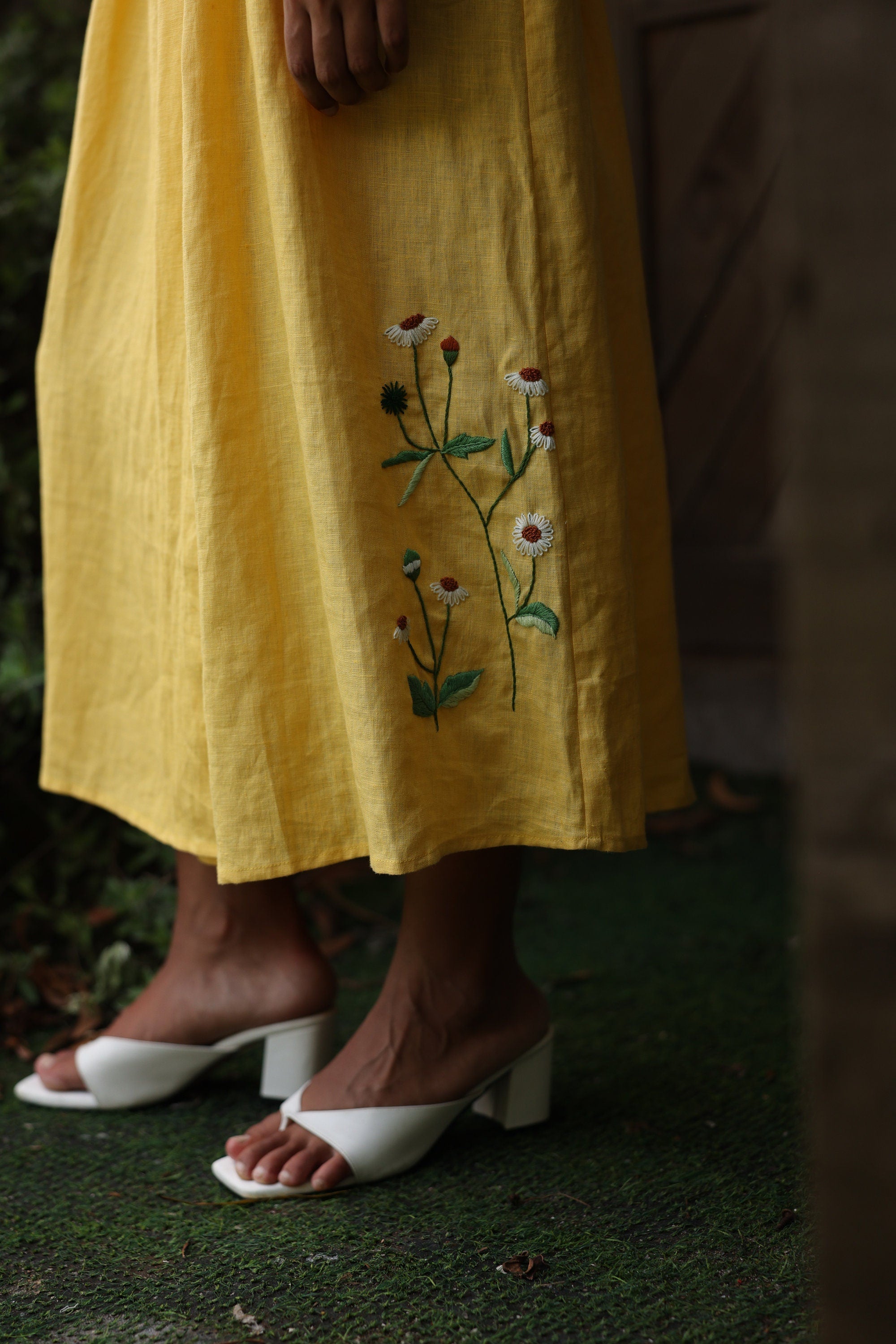 Yellow dress with floral embroidery worn by a person on a grassy background