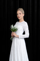 Woman in a white dress holding flowers against a black background