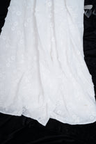 Close-up of a white floral garment with black background
