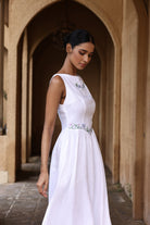 Woman in a white dress standing in an arched stone corridor
