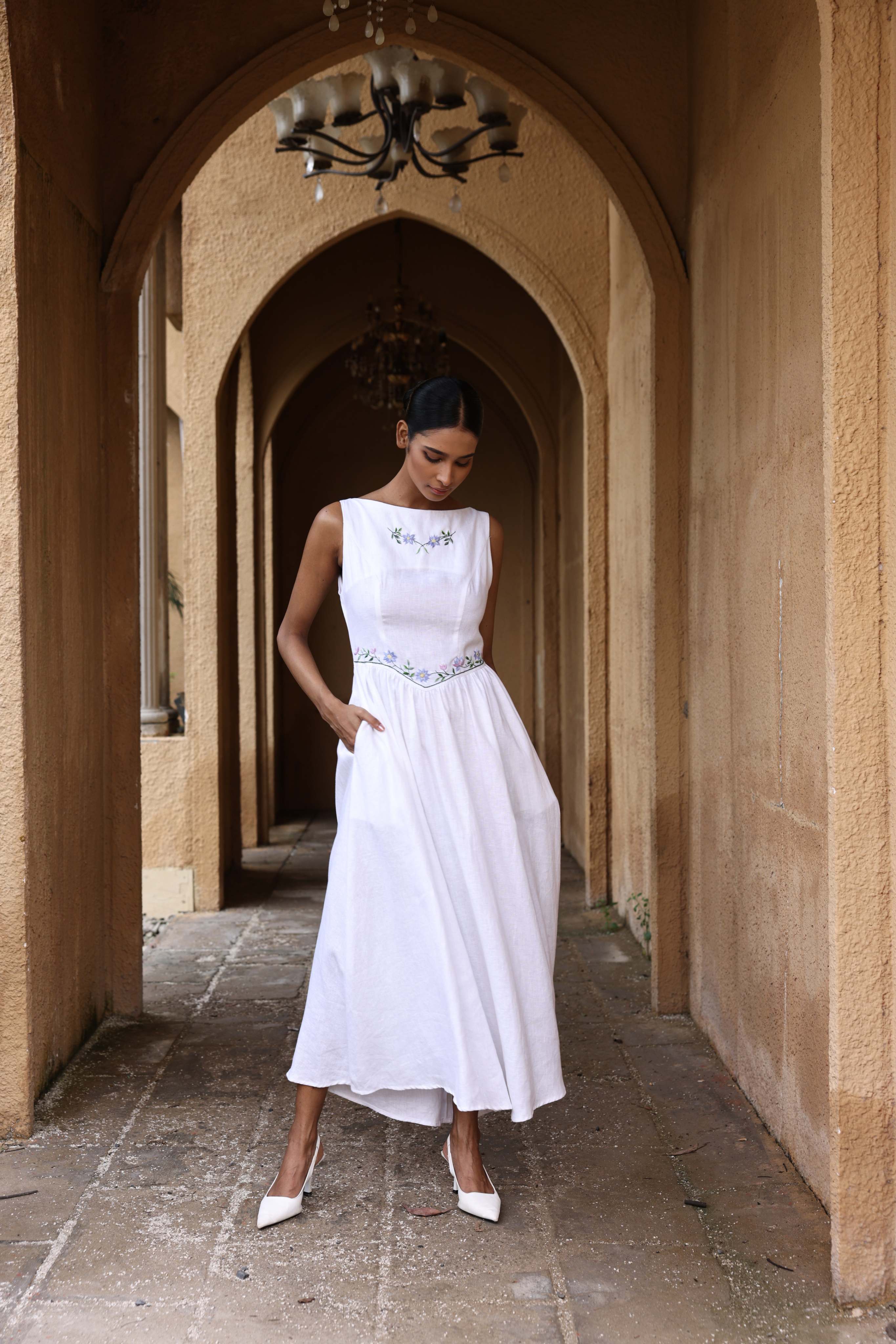 Woman in a white dress standing in an arched stone hallway