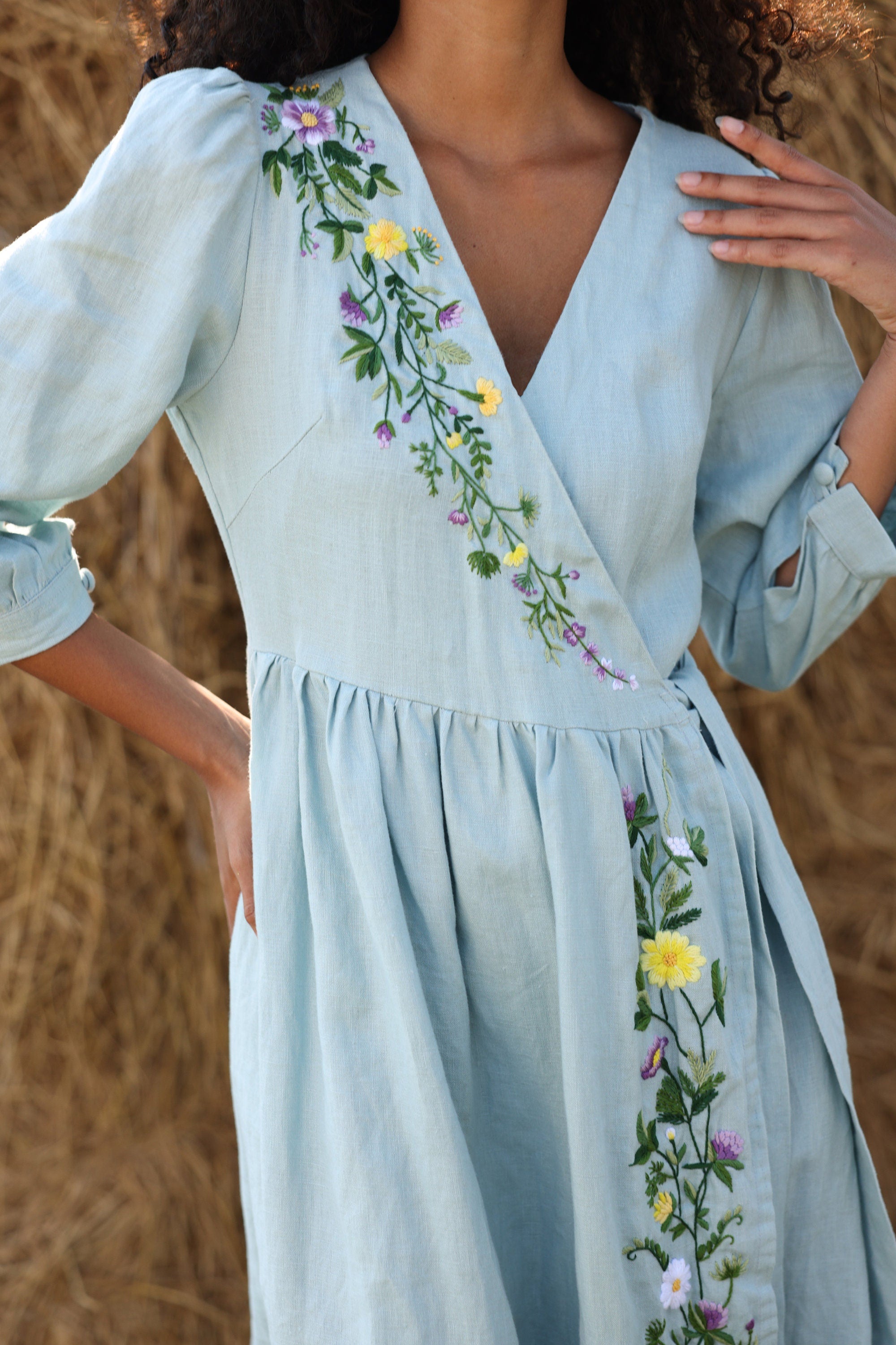 Light blue dress with floral embroidery on a blurred natural background
