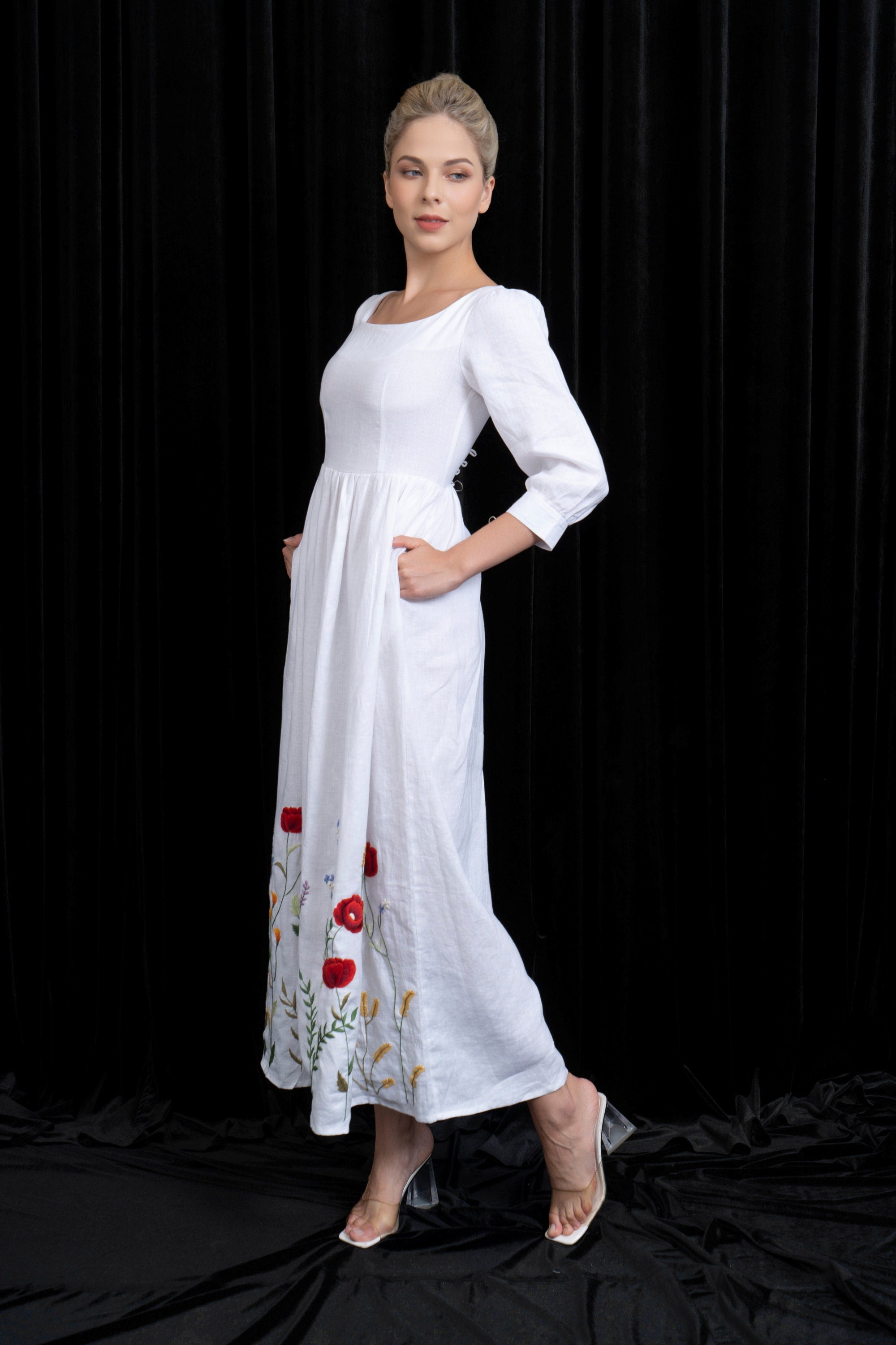 Woman wearing a white dress with floral embroidery on a black background