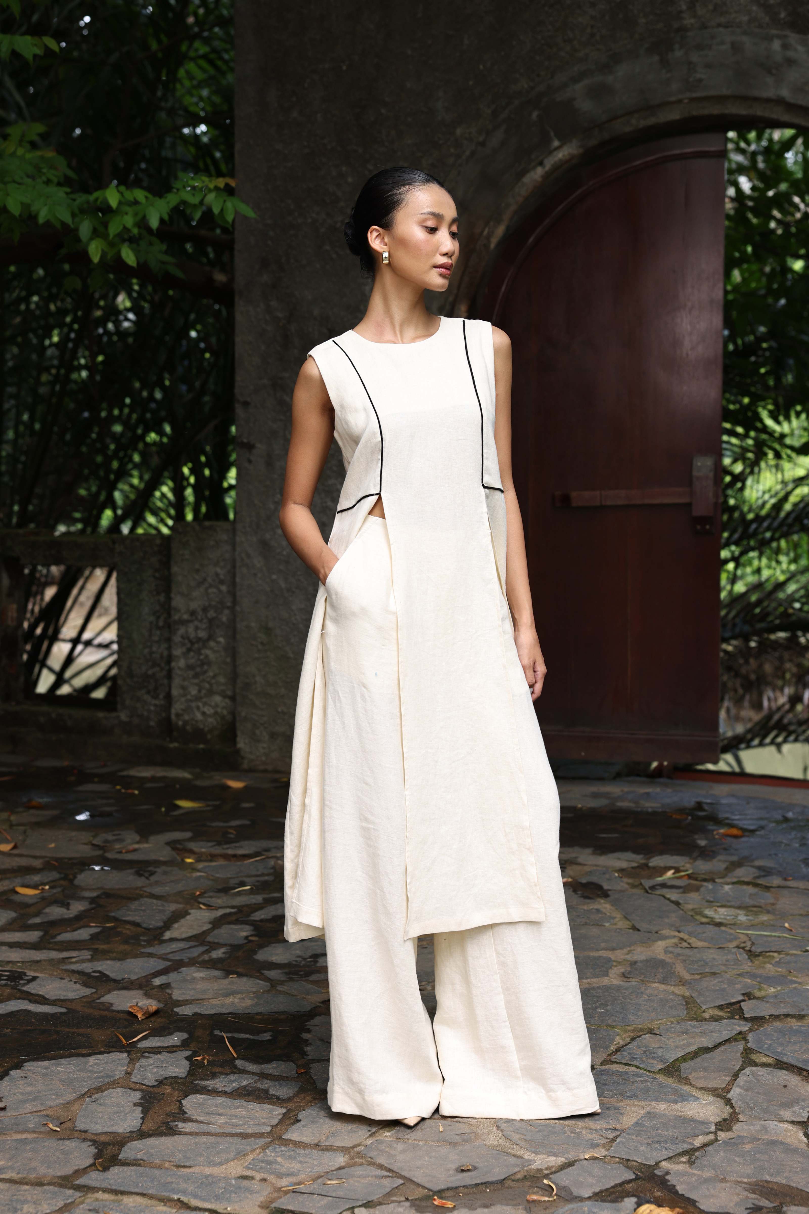 Woman in a white dress standing outdoors with a large bell in the background