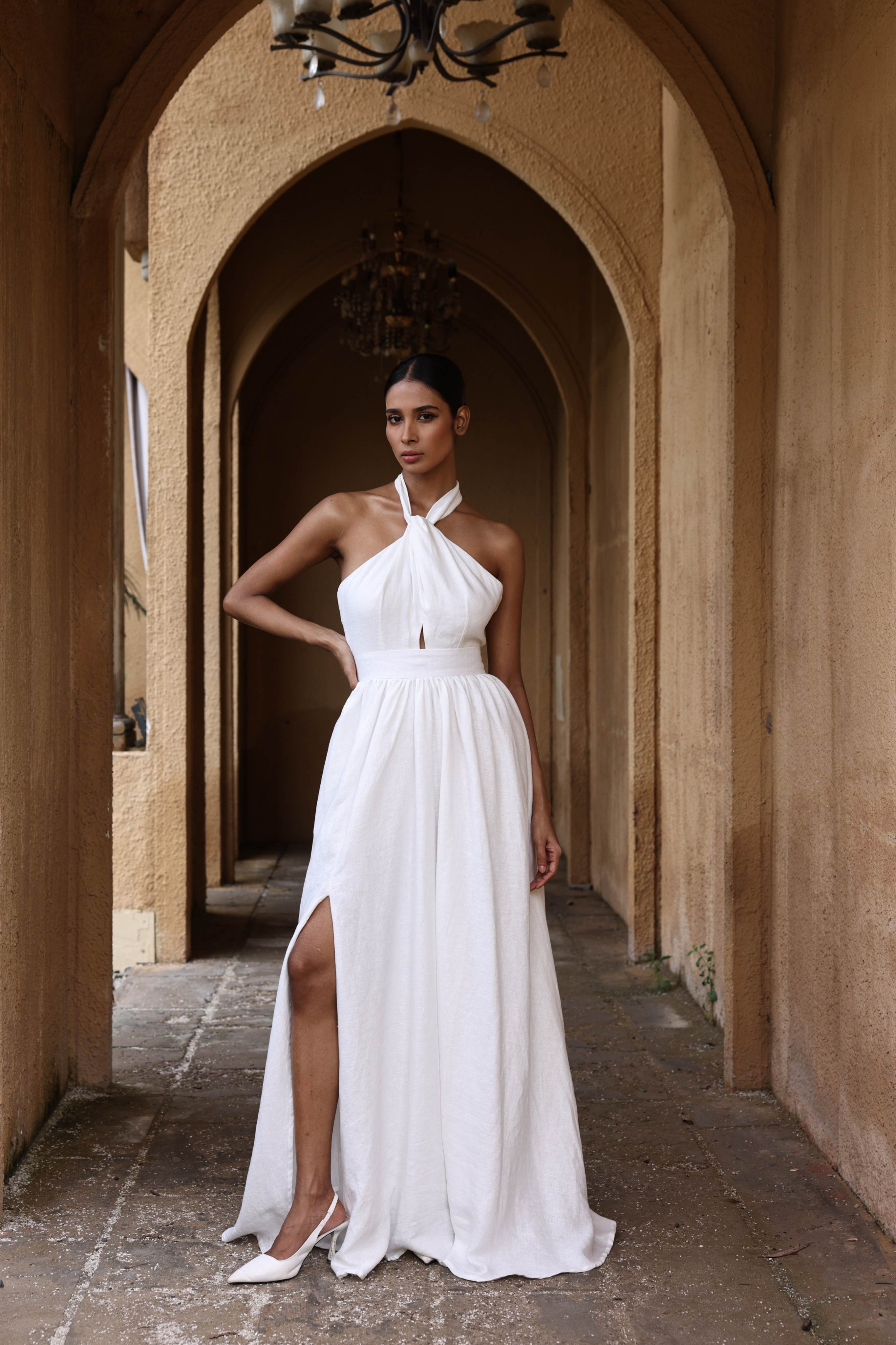 Woman in a white dress standing in an arched stone corridor