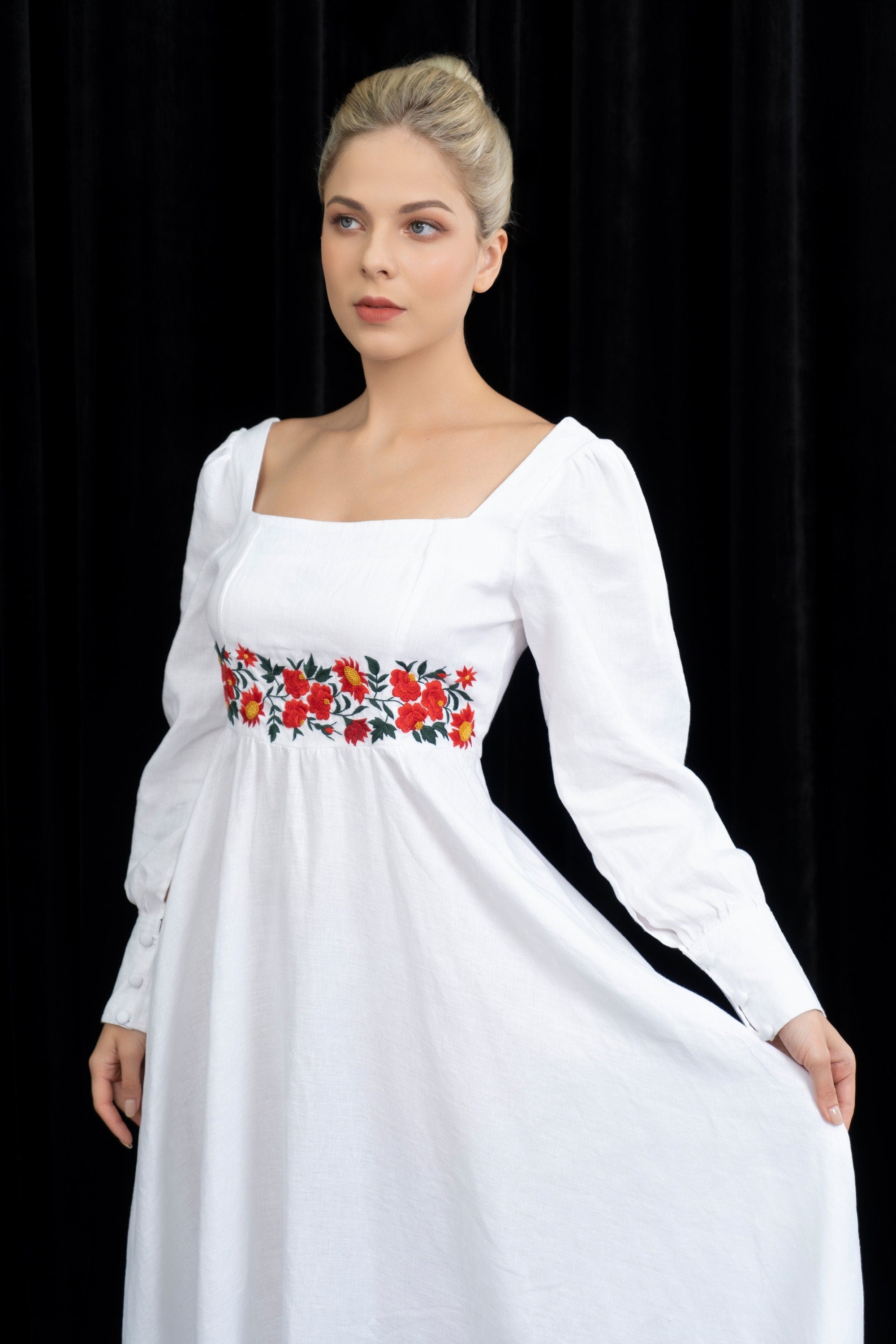 Woman wearing a white dress with floral embroidery on a black background