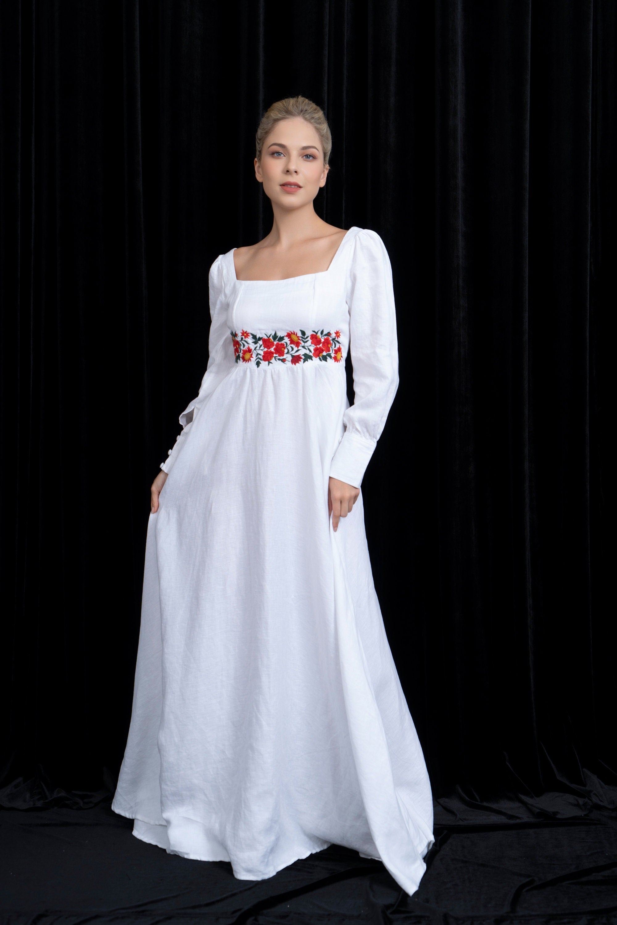 Woman wearing a white dress with floral embroidery on a black background