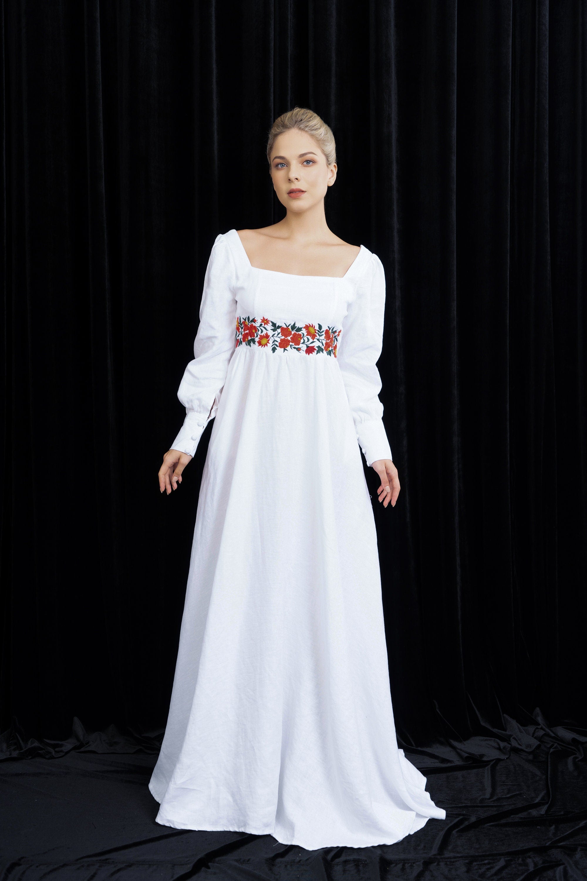 Woman wearing a white dress with floral embroidery on a black background