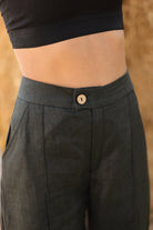 Person wearing dark gray pants with a button on a blurred background