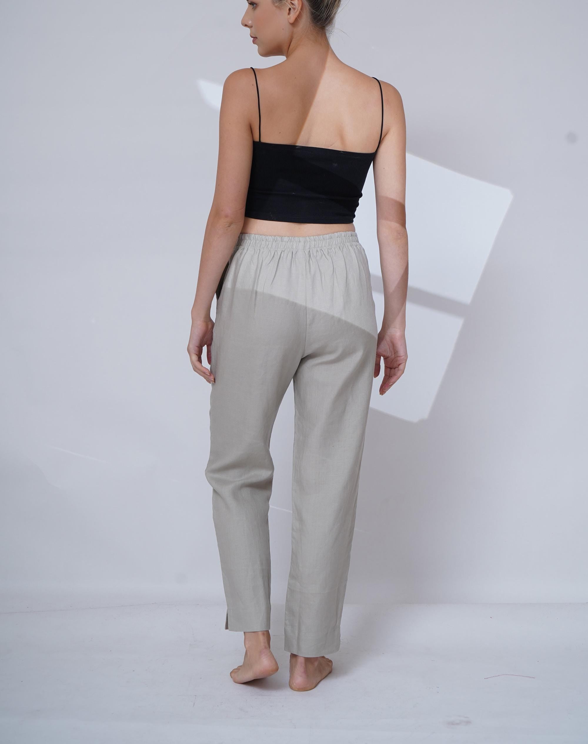 Person wearing a black top and light gray pants on a white background