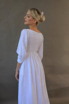 Woman wearing a white dress against a plain background