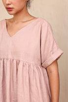 Person wearing a pink top against a beige background
