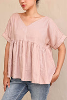 Person wearing a pink blouse and blue jeans on a beige background
