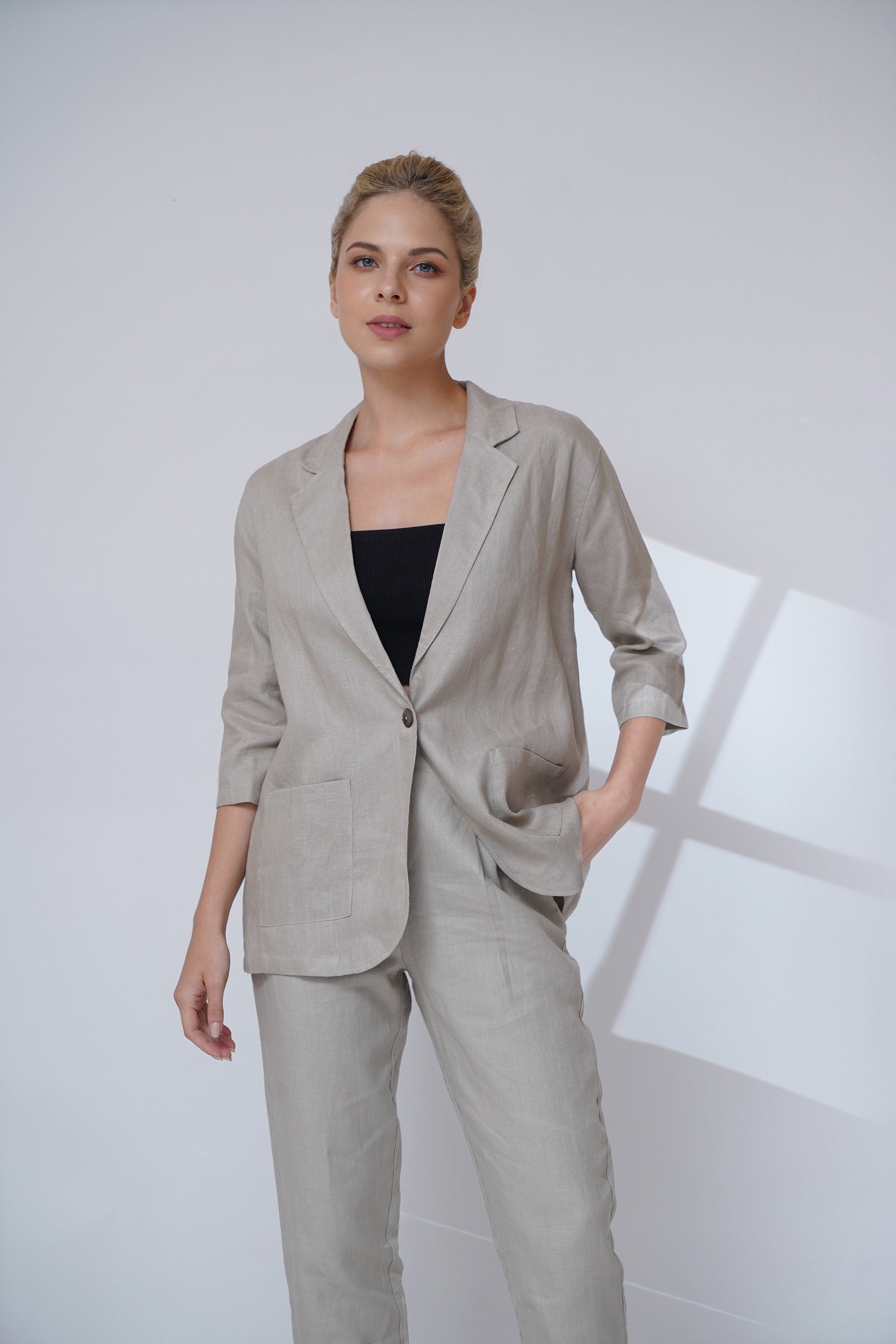 Woman wearing a suit with a black top against a white background