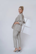 Woman wearing a light gray suit standing against a white background