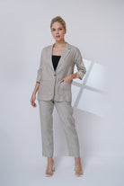 Woman wearing a beige suit standing against a white background