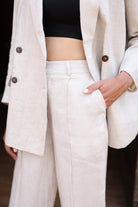 Person wearing a beige coat and pants with a blurred background