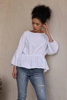 Woman wearing a white blouse and blue jeans against a beige background