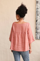 Person wearing a pink blouse with a neutral background