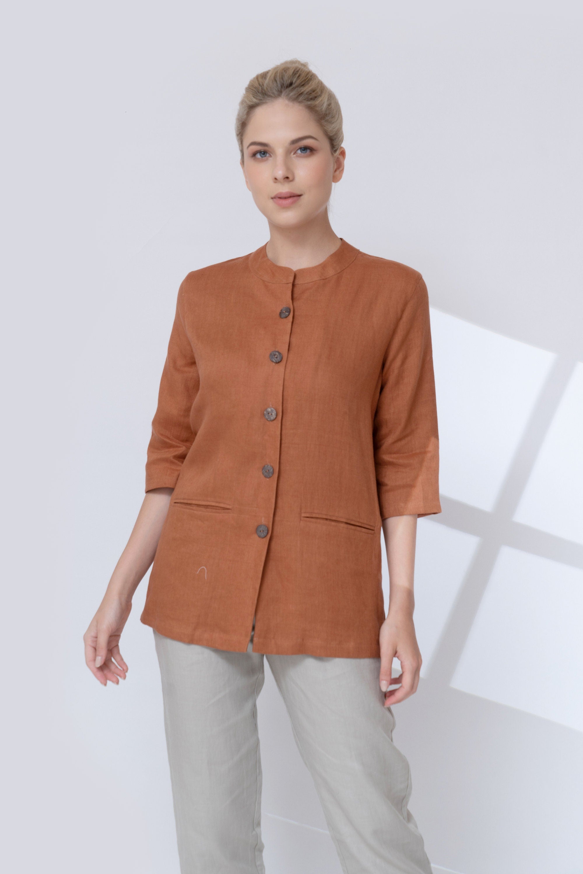 Woman wearing a brown jacket with buttons on a white background