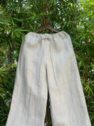 Pants on a hanger against a green leafy background