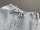 Light gray linen top with drawstring on a concrete surface