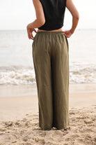 Person wearing olive green pants and black top on a beach