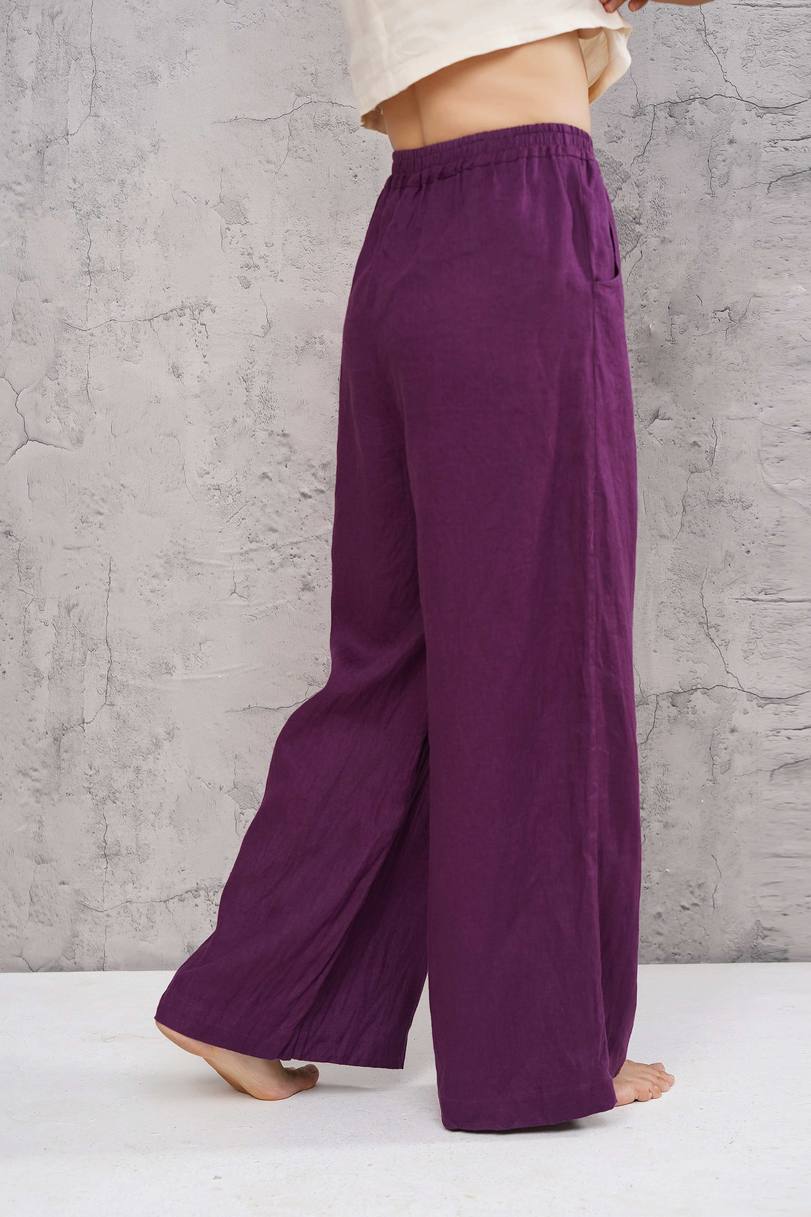 Purple wide-leg pants worn by a person against a gray concrete wall.