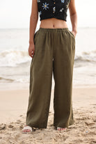 Person wearing olive green wide-leg pants on a beach