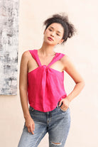 Woman wearing a bright pink top and blue jeans against a neutral background